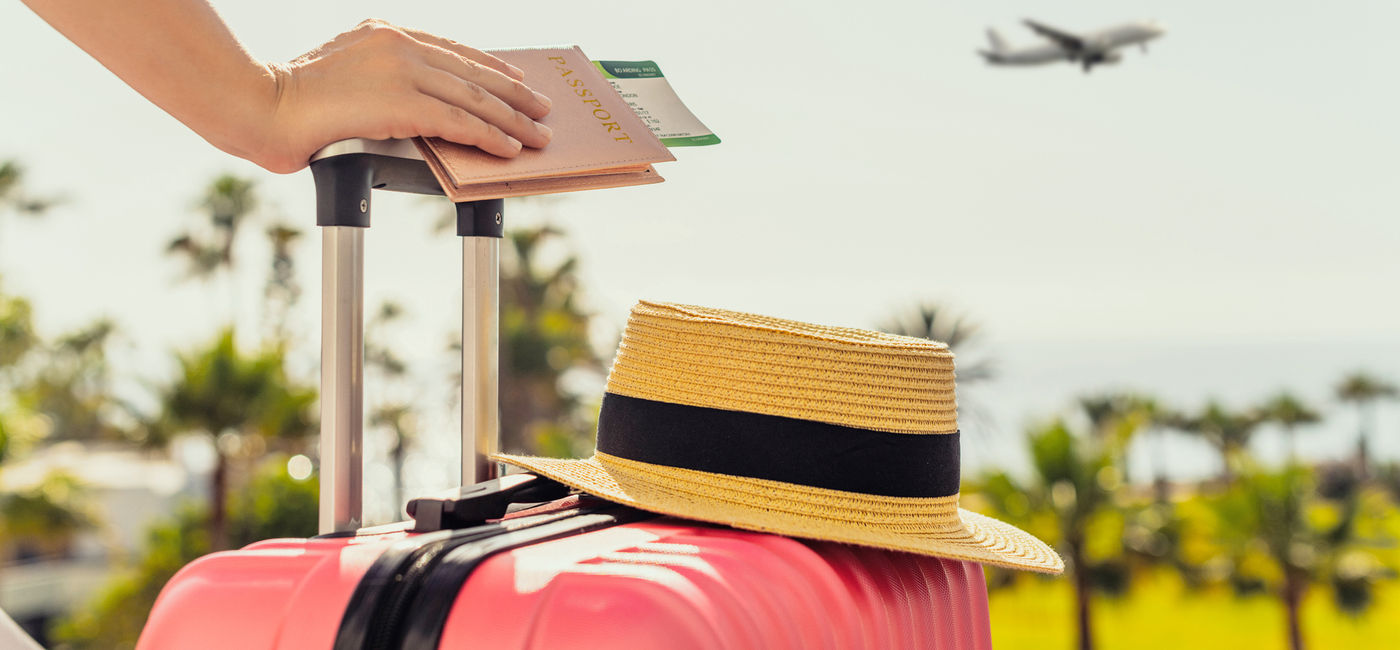 Image: Female traveler with a suitcase at the airport (photo courtesy FTiare/iStock / Getty Images Plus)